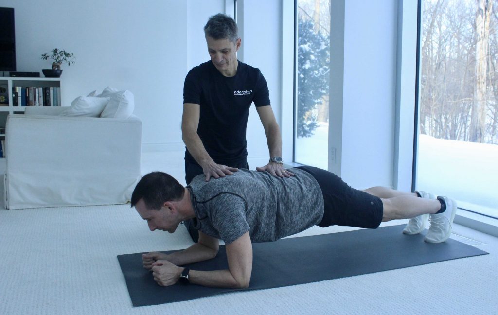 Neil helping a client maximize the effectiveness of a plank exercise.